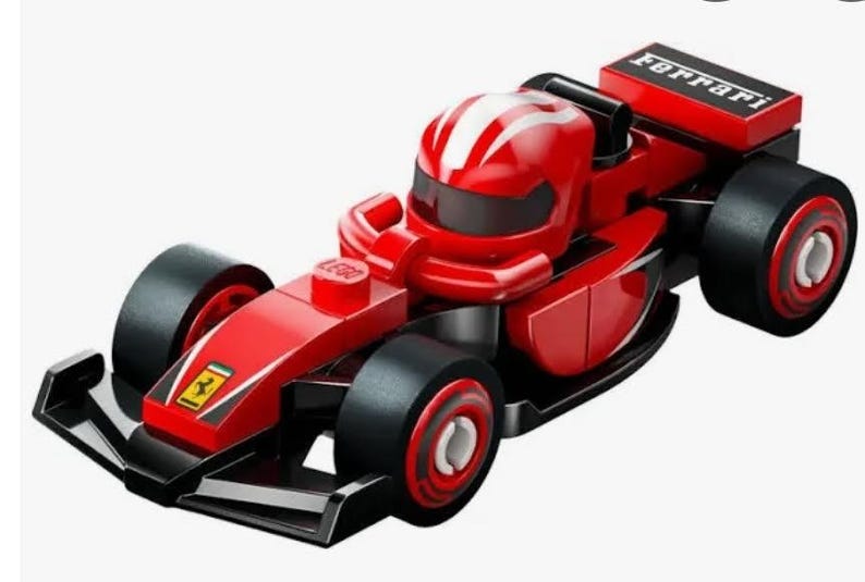 May include: A red Lego Ferrari Formula 1 race car with black wheels and a white stripe on the driver's helmet. The car has the word "Ferrari" printed on the back.
