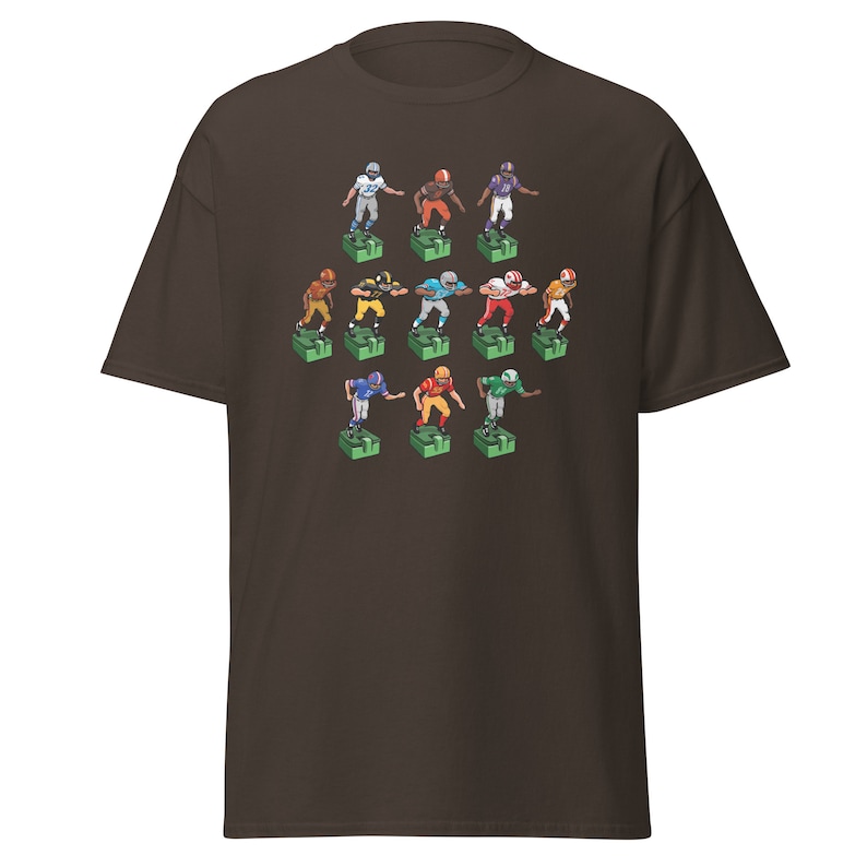 Short sleeve t-shirt with 11 retro style electric football game players printed across the front. Each player is roughly 2 inches by 3 inches and wearing different colorful uniforms. Dark brownish-olive shirt.