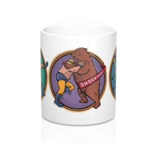 Coffee cup with 3 pictures around it- colorful illustrations of a masked wrestler battling a bear, giant rabbit, and alligator. Cup is white and holds 11 ounces of your favorite drink.