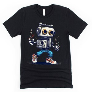 Może przedstawiać: Czarny t-shirt z kresk&oacute;wkowym robotem w niebieskich dżinsach i butach sportowych. Robot trzyma mikrofon i ma retro design.