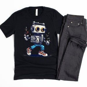 Może przedstawiać: Czarny t-shirt z kresk&oacute;wkowym robotem w niebieskich dżinsach i butach sportowych. Robot ma retro design i trzyma mikrofon. T-shirt jest w parze z ciemnoszarymi dżinsami.