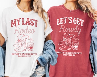 May include: Two white t-shirts with red text and graphics. The first shirt says "My Last Rodeo" with a drawing of cowboy boots and a glass of whiskey. The second shirt says "Let's Get Rowdy" with a drawing of cowboy boots and a glass of whiskey. Both shirts say "Hayley's Bachelorette Nashville, TN".