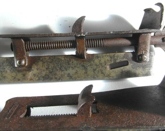 May include: Close-up of a rusty metal clamp with a threaded screw and a lever. The clamp is open and the screw is visible. The clamp is made of metal and has a rough, textured surface.