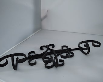 Op de afbeelding: Zwarte metalen wanddecoratie met een decoratief ontwerp. Het ontwerp bestaat uit een reeks swirls en lussen, waardoor een uniek en opvallend stuk ontstaat.