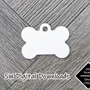 Op de afbeelding: Een wit, botvormig hondenlabel met een gat voor een ring. Het label is leeg en klaar om te worden gepersonaliseerd. Het label bevindt zich op een houtnerf achtergrond. De tekst "SW Digital Downloads" bevindt zich onder het label. Een zwarte ruit met de tekst ".PSD Format Smart Object" bevindt zich in de rechter benedenhoek.