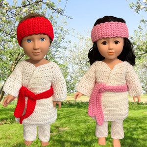 May include: Two dolls wearing white crocheted karate outfits. One doll has a red headband and a red belt, while the other doll has a pink headband and a pink belt.