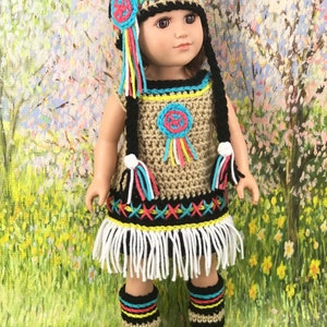 May include: A crochet doll outfit in Native American style, featuring a dress, leggings, and a hat with fringe. The outfit is in shades of brown, black, white, red, yellow, and blue.