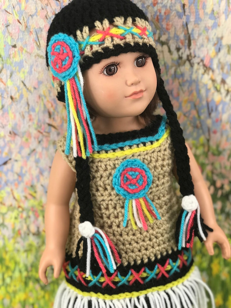 May include: A crocheted doll outfit in brown, black, white, yellow, blue, pink, and red. The outfit includes a dress with fringe, a hat with fringe, and a beaded design.