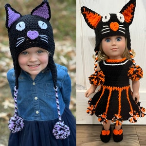May include: Two crocheted black cat hats with orange and white pom-poms. One hat is worn by a child and the other is worn by a doll.