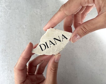 May include: A white stone with the name "DIANA" written in black lettering.