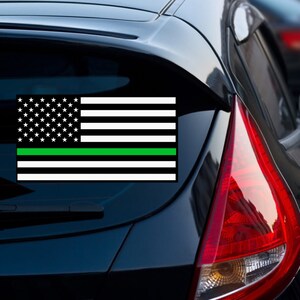 Puede incluir: Un coche negro con una calcoman&iacute;a de bandera estadounidense con una l&iacute;nea verde en la ventana trasera.