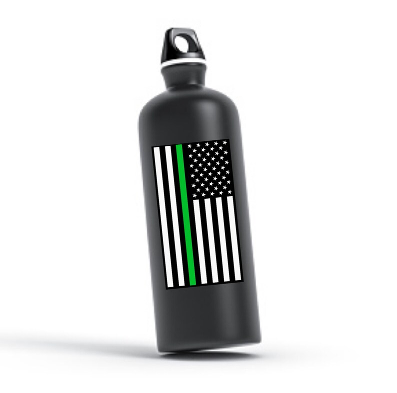 Puede incluir: Botella de agua negra con una fina l&iacute;nea verde en el centro de un dise&ntilde;o de bandera estadounidense.