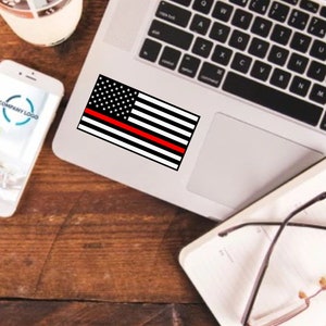 May include: A black and white American flag sticker with a single red stripe across the middle, placed on a laptop computer.