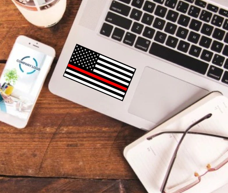 May include: A black and white American flag sticker with a single red stripe across the middle, placed on a laptop computer.