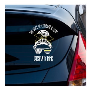 Puede incluir: Una pegatina de vinilo blanco con un dise&ntilde;o de bandera de l&iacute;nea fina negra y amarilla. La pegatina presenta a una mujer de dibujos animados con un mo&ntilde;o y gafas de sol. El texto "The Voice of Courage & Hope" y "Dispatcher" est&aacute;n en la pegatina.