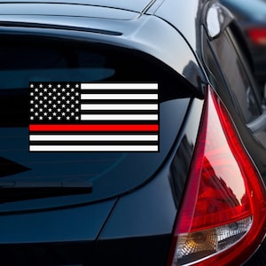May include: A black and white American flag with a thin red stripe across the middle. The flag is on a black car.