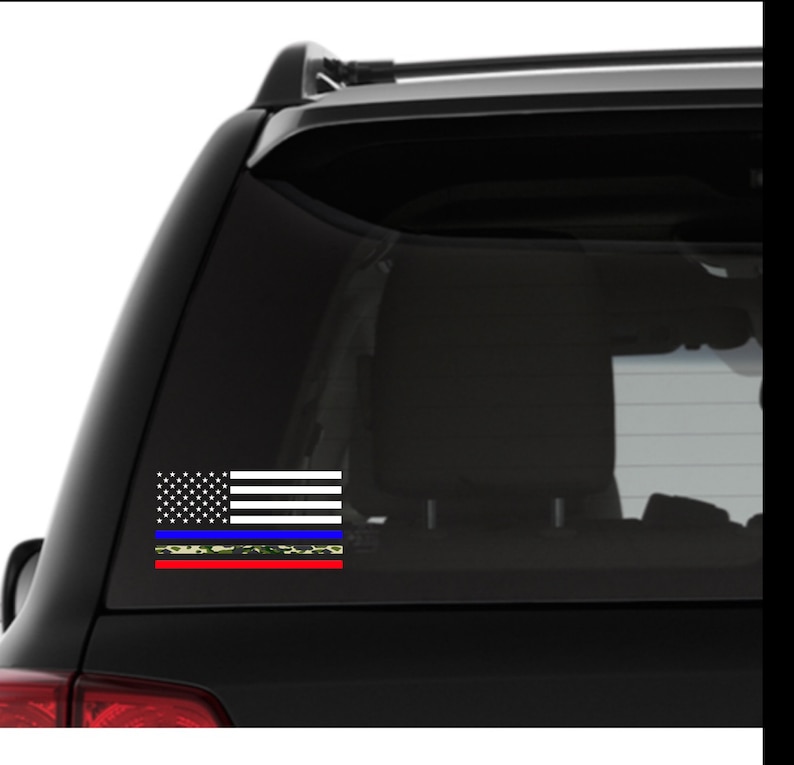 Puede incluir: Un coche negro con una calcoman&iacute;a de bandera estadounidense blanca, roja y azul en la ventana trasera. La bandera tiene una l&iacute;nea azul fina y una l&iacute;nea roja fina con un patr&oacute;n de camuflaje.