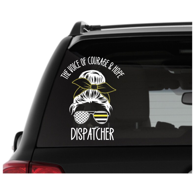 Puede incluir: Una calcoman&iacute;a de ventana de autom&oacute;vil blanca con un gr&aacute;fico negro y amarillo de una mujer con un mo&ntilde;o, gafas de sol y una cinta. El texto dice "The Voice of Courage & Hope Dispatcher".