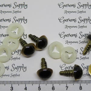 Puede incluir: Surtido de ojos de seguridad marrones con pupilas negras y arandelas de metal dorado. Los ojos est&aacute;n unidos a arandelas de pl&aacute;stico con un tornillo. La imagen tambi&eacute;n incluye el texto "Gurumi Supply Amigurumi Supplies".