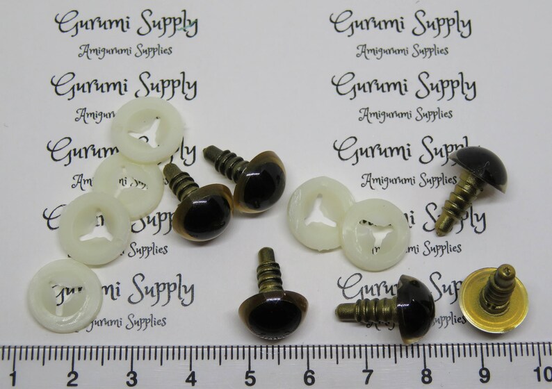 Puede incluir: Surtido de ojos de seguridad marrones con pupilas negras y arandelas de metal dorado. Los ojos est&aacute;n unidos a arandelas de pl&aacute;stico con un tornillo. La imagen tambi&eacute;n incluye el texto "Gurumi Supply Amigurumi Supplies".