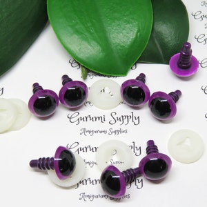 May include: Purple plastic safety eyes with black pupils and a screw back. The eyes are on a white surface with white plastic washers.