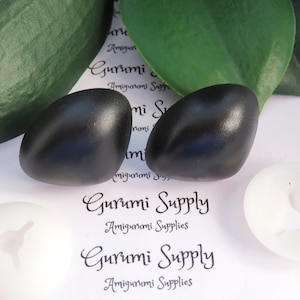 Puede incluir: Dos ojos de seguridad de plástico negro para proyectos de amigurumi. Los ojos son brillantes y tienen un ligero brillo. Los ojos están sobre un fondo blanco con el texto "Gurumi Supply Amigurumi Supplies" impreso en él.