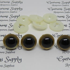 Puede incluir: Seis ojos de seguridad de pl&aacute;stico con borde dorado y pupilas negras. Los ojos est&aacute;n dispuestos en dos filas de tres. Los ojos est&aacute;n sobre un fondo blanco con el texto "Gurumi Supply" impreso en el fondo.