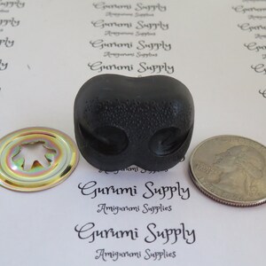 May include: A black plastic safety eye with a textured surface. The eye is about the size of a US quarter. The eye is used for amigurumi projects.