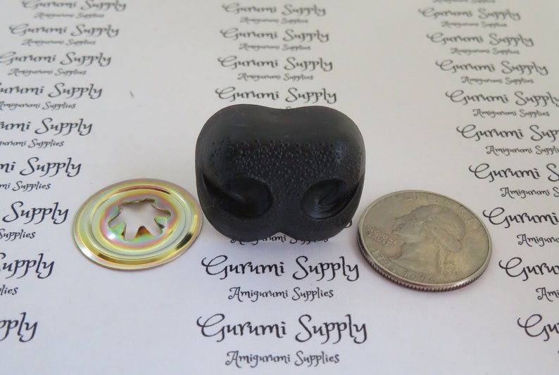 May include: A black plastic safety eye with a textured surface. The eye is about the size of a US quarter. The eye is used for amigurumi projects.