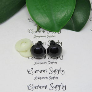 May include: Two black plastic safety eyes with a white washer, used for amigurumi projects. The eyes are on a white background with the text "Gurumi Supply Amigurumi Supplies" printed on it.