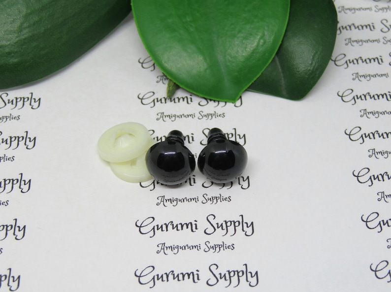 May include: Two black plastic safety eyes with a white washer, used for amigurumi projects. The eyes are on a white background with the text "Gurumi Supply Amigurumi Supplies" printed on it.