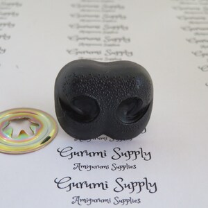 May include: Black plastic safety eyes for amigurumi projects. The eyes have a textured surface and are approximately 1 inch in diameter.