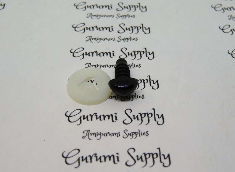 May include: A close-up of a black plastic safety eye for amigurumi projects. The eye is attached to a white plastic washer. The image is on a white background with the text "Gurumi Supply Amigurumi Supplies" printed on it.