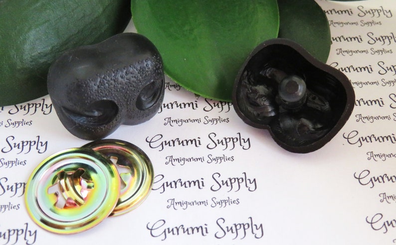 May include: Two black plastic safety eyes for amigurumi projects, with a textured surface. The eyes are 18mm in diameter and come with two iridescent metal washers.