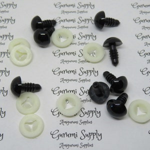 May include: A close-up of black plastic safety eyes with white plastic washers. The eyes are about 12 mm in diameter and have a screw-on back.