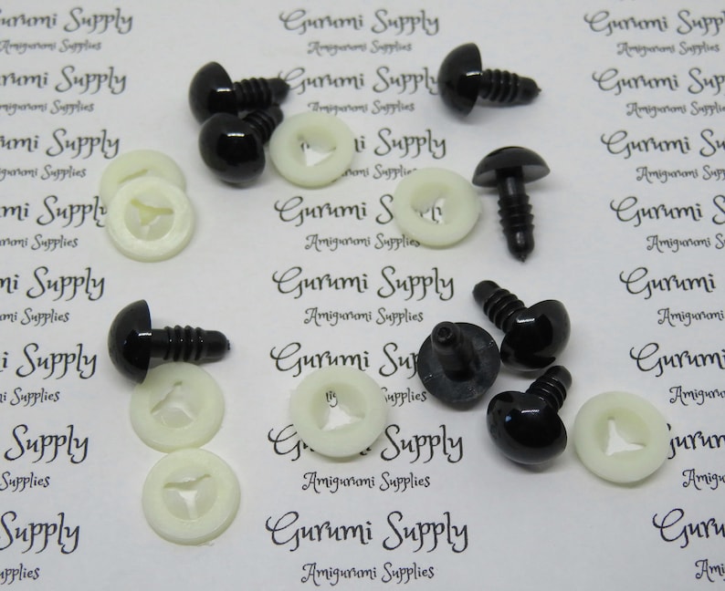 May include: A close-up of black plastic safety eyes with white plastic washers. The eyes are about 12 mm in diameter and have a screw-on back.