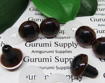 Puede incluir: Una colección de ojos de seguridad de plástico marrón para proyectos de amigurumi, con tallos negros y arandelas blancas. El texto "Gurumi Supply" y "Amigurumi Supplies" es visible. Los ojos son de color marrón oscuro y tienen un acabado brillante.
