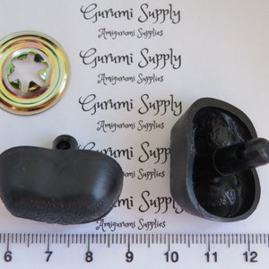 May include: Two black plastic buttons with a textured surface and a small black knob on top. A gold metal button with a star-shaped hole in the center is also included. The buttons are measured on a ruler in inches.