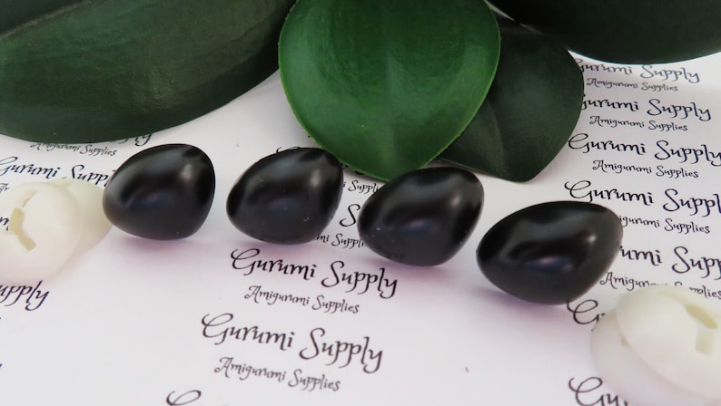 May include: Five black plastic safety eyes for amigurumi projects. The eyes are oval shaped and have a glossy finish.