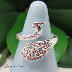 May include: Silver ring with a peacock design. The ring is open and adjustable. The peacock is facing to the right and has a detailed design.