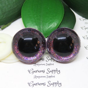 May include: Pair of black and purple glitter safety eyes for amigurumi projects. The eyes have a black pupil and a purple glitter surrounding the pupil. The eyes are 12mm in diameter.