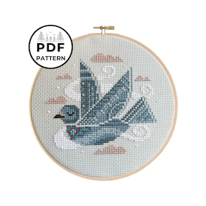 May include: A cross-stitch pattern featuring a blue bird flying through a cloudy sky. The bird has a pink and green scarf. The pattern is in a circular embroidery hoop.
