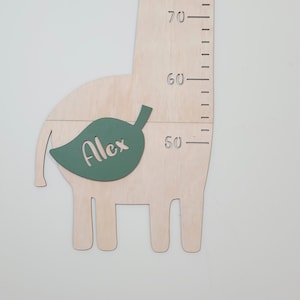 May include: A wooden giraffe growth chart with a green leaf cutout that says "Alex" on it. The chart has a ruler on the side that goes up to 70 inches.