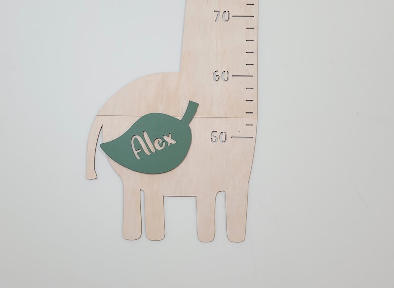 May include: A wooden giraffe growth chart with a green leaf cutout that says "Alex" on it. The chart has a ruler on the side that goes up to 70 inches.
