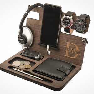 May include: A wooden organizer with compartments for a phone, watch, keys, and wallet. The organizer has a personalized name, "DAVID", engraved on the front.