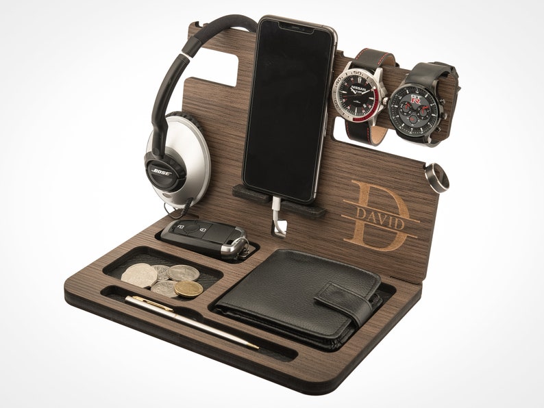 May include: A wooden organizer with compartments for a phone, watch, keys, and wallet. The organizer has a personalized name, "DAVID", engraved on the front.