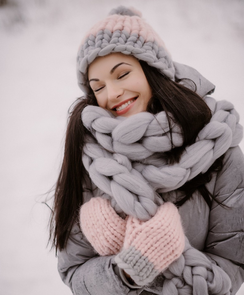 Lady feeling cozy outdoors in winter with chunky knit scarf and hat with gloves