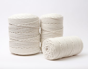 Puede incluir: Tres carretes de cuerda de algodón natural, cada uno enrollado en una dirección diferente. La cuerda es gruesa y tiene un color natural blanquecino.