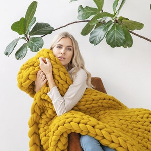 Lady cuddling with chunky knit blanket in mustard