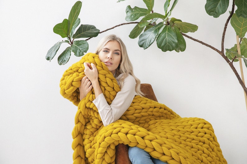 Lady cuddling with chunky knit blanket in mustard